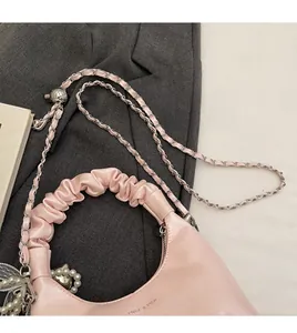 Detail of pink pleated handbag with silver chain strap and decorative pearl pendant