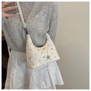 Detail of white quilted hobo bag featuring silver rivets and rhinestone star on model