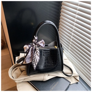 Détail du sac noir à texture crocodile avec foulard en soie et logo de marque embossé