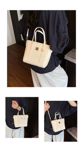 Detail view of cream white bucket bag with pebble leather texture and gold buckle