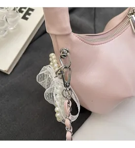 Detail of light pink pleated handbag with lace bow pearl charm and silver chain strap