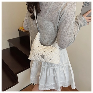 Detail shot of white quilted shoulder bag with star hardware shown on model's shoulder