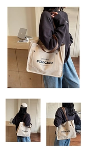 Detail of off-white canvas tote bag with brown leather strap and metal buckle pocket