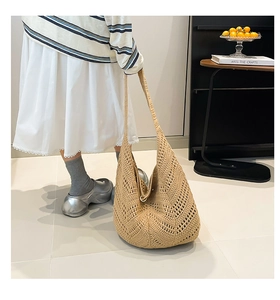 Detail of hand-woven hollow hobo shoulder bag in khaki on model with stripe shirt