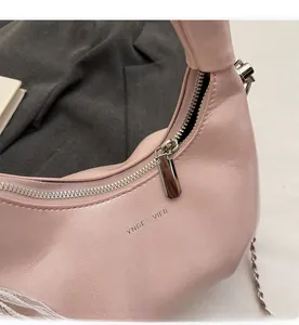 Detail shot of smooth silver metal zipper and brand logo on a pink ruched handbag
