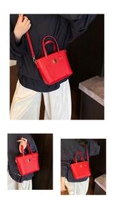 Detail view of the red leather tote bag with gold metal hardware and adjustable strap