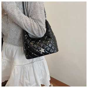 Detailed shot of black quilted bag with silver star and rivets on shiny PU leather