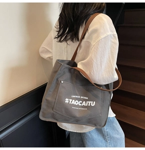 Detail of grey canvas tote bag with front pocket and contrast brown leather strap