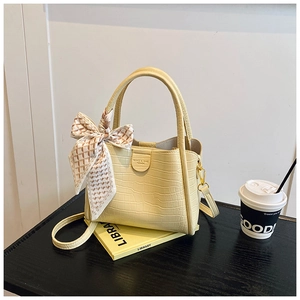 Détail d'un sac à main beige motif crocodile avec foulard en soie et finitions dorées