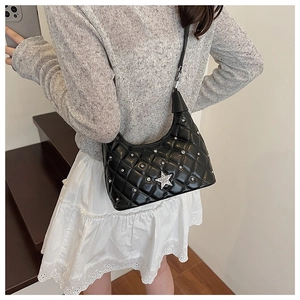 Detailed view of black hobo bag with silver star and studs on grey sweater background