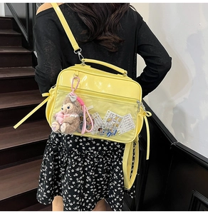 Detail of yellow patent leather ita bag with a clear window and plush bear pendant