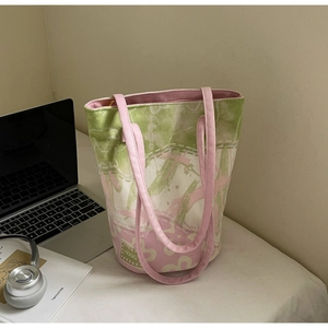 Détail du sac cabas en toile bicolore rose et vert avec étiquette tissée sur un bureau