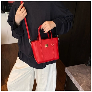 Close-up of bright red lychee grain leather handbag with gold buckle and slim strap