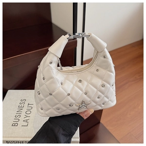 Close-up of white quilted underarm bag featuring silver rivets and rhinestone star detail