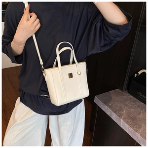 Detail of cream white leather bucket bag with gold hardware and grainy texture