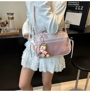 Detail of pink ita bag with clear PVC window and a brown plush bear keychain