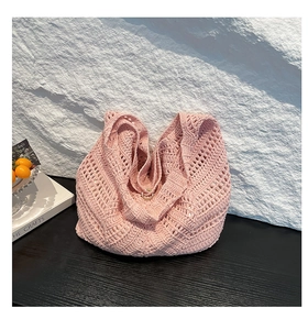Detail of pink crochet shoulder bag showing hollow knit wave texture and metal rings