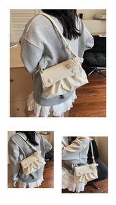 Détail d'un sac plissé blanc avec breloque fleur en perles et finition brillante