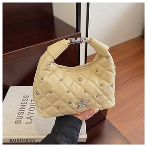 Close-up of yellow quilted bag featuring star rhinestone emblem and silver rivet details