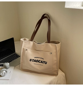 Detail of beige canvas tote with rivet pocket and dark brown leather shoulder straps
