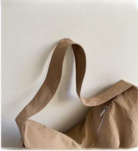 Detail of sturdy shoulder strap stitching and silver zipper on khaki woven tote bag