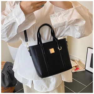 Detail view of black pebble leather tote bag with gold hardware and detachable strap
