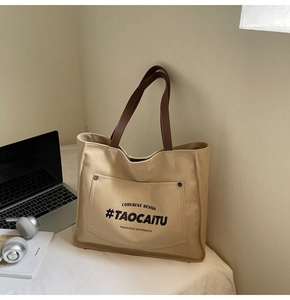 Detail of canvas tote bag showing front pocket with metal rivets and sturdy brown handles