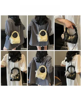 Detail view of stylish pleated handbag with metal chain and elegant bow charms