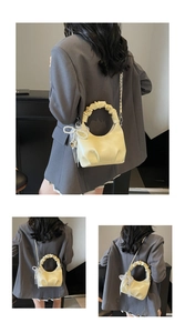 Close-up of creamy yellow pleated handbag featuring pearl bow charm and chain strap detail