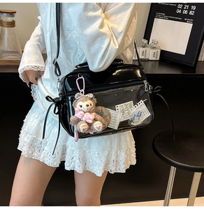 Detail of black PVC ita bag featuring transparent window and plush mascot charm