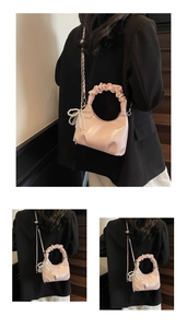Detail of light pink pleated handle handbag featuring pearl bow charm and metal chain