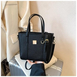 Close-up of black lychee grain texture and gold square metal buckle on tote bag