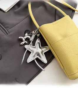 Detail of yellow lychee leather crossbody bag with silver balloon dog and star charms