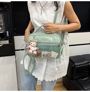 Detail view of mint green patent leather bag with clear pocket and purple plush bunny charm