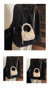 Detail of a chic ruched cream handbag with pearl chain and metallic heart charm