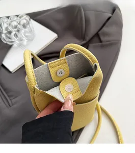 Detailed view of the yellow lychee grain leather mini bucket bag with magnetic snap closure