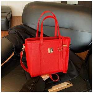 Close-up of bright red lychee leather bag with gold metal logo and detailed texture