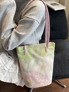 Sac fourre-tout en toile florale rose et vert porté par un mannequin en style décontracté
