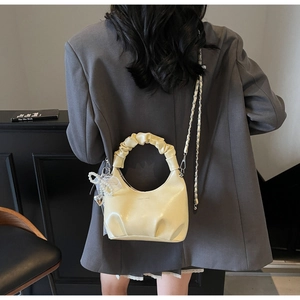 Detail of beige pleated handbag with heart pearl charm and braided chain strap
