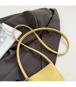 Detail of a yellow lychee-grain leather mini shoulder bag on a dark blazer