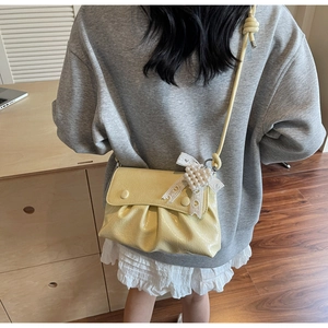 Détail du sac bandoulière plissé jaune avec ruban en dentelle coeur et perles
