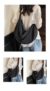 Detail of minimalist black nylon crescent tote bag showing crossbody style and zipper
