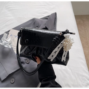 Détail du sac à main plissé noir avec breloque cœur en perles et dentelle élégante
