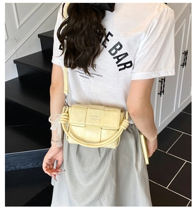 Détail du sac à bandoulière tissé jaune avec poignée torsadée présenté sur un mannequin