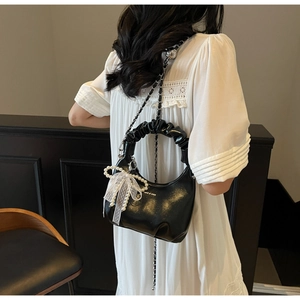 Detail of black pleated leather hobo bag with pearl lace charm and chain strap