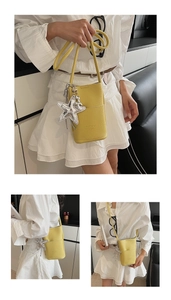 Detail of yellow pebbled leather crossbody phone bag with starfish charm and strap