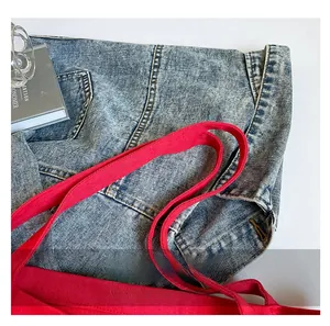 Close-up of washed blue denim fabric with contrasting bright red cotton ribbon handles