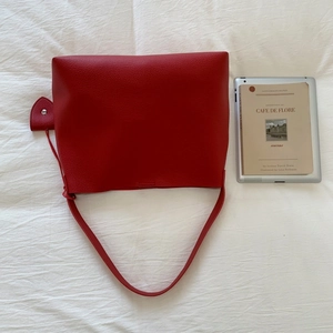 Close-up of red lychee grain leather tote bag with thin strap and semi-circular pendant