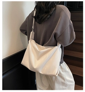 Model wearing large off-white crossbody canvas bag showing spacious casual design