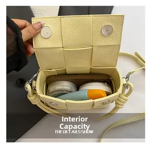 Détail de la capacité intérieure du sac à bandoulière jaune tressé avec accessoires
